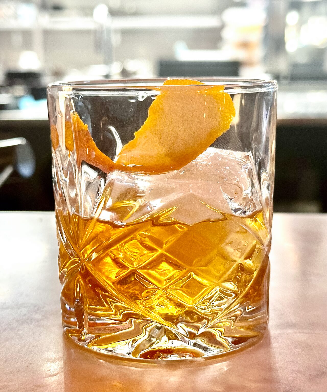 Drink i kristallglas med is och apelsinskal på bardisken